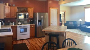 Une cuisine moderne avec des meubles en bois, des appareils en acier inoxydable et un îlot central doté de tabourets.