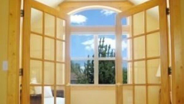 Une pièce dotée d’une grande fenêtre en arc de cercle, d’une porte en bois et d’un plancher recouvert de moquette.