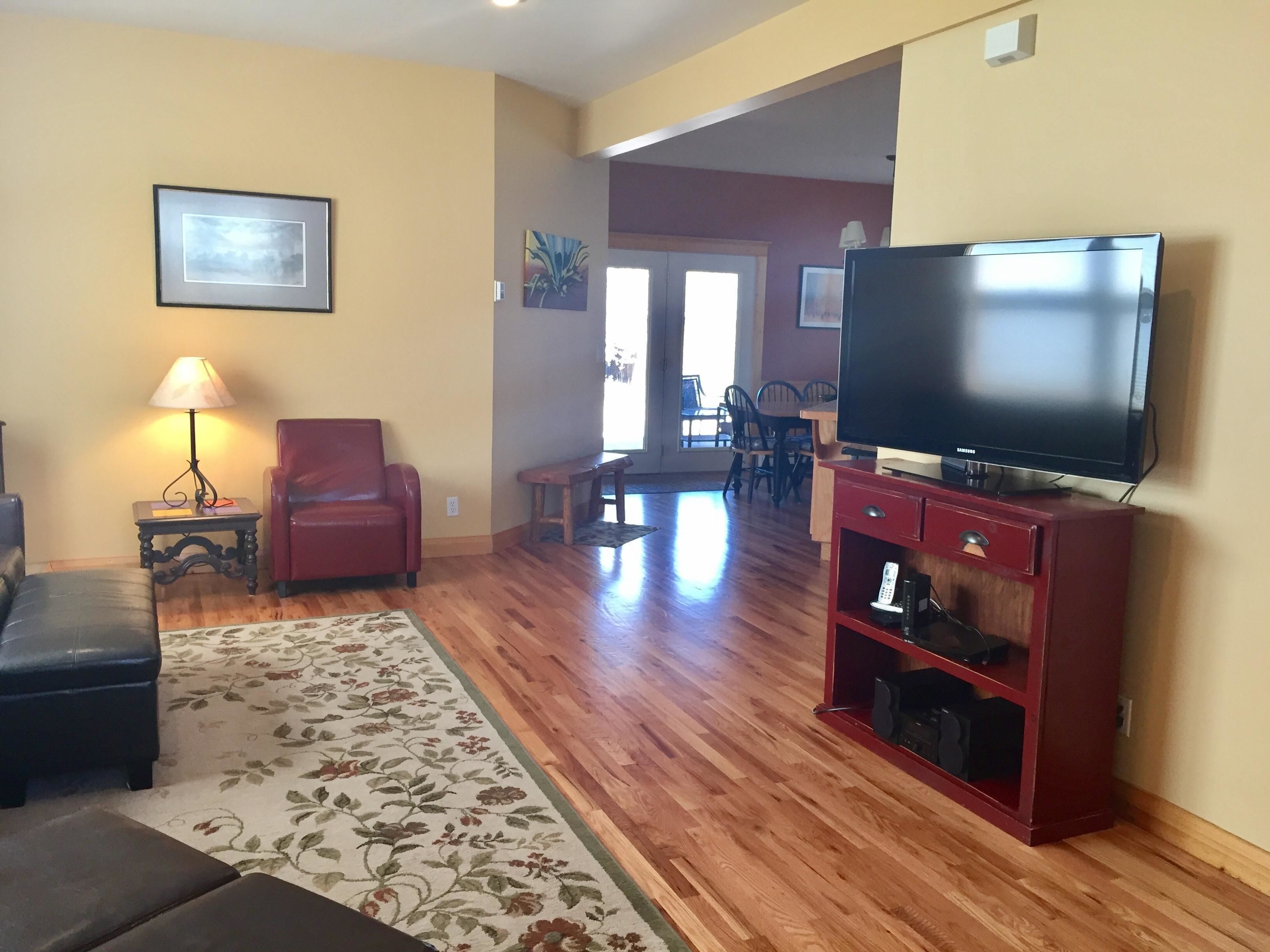 A living room with a red sofa, a TV on a wooden stand, a lamp, and a floral rug.