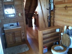 Ein Badezimmer einer Holzhütte mit einem Holzwaschbecken, einer Toilette und einem Spiegel.