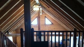 An attic room with wooden beams, a sloped ceiling, and a view of the lower level. - Mt Princeton Escape 1 Bedroom Holiday Home By Pinon Vacation Rentals (Nathrop)