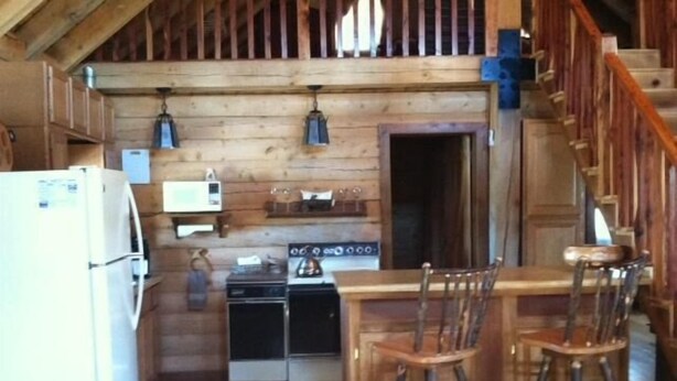 A rustic kitchen with wooden walls, a refrigerator, a stove, and two bar stools. - Mt Princeton Escape 1 Bedroom Holiday Home By Pinon Vacation Rentals (Nathrop)