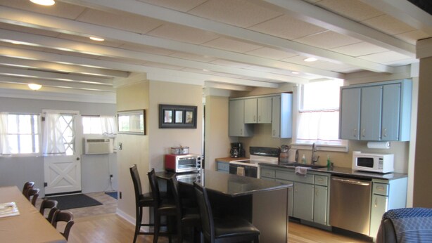 A kitchen with wooden flooring, a dining table with chairs, and a small island. - Nita s Place 2 Bedroom Holiday Home By Pinon Vacation Rentals (Salida)