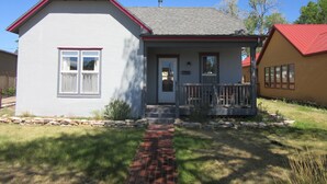 A two-story house with a front porch, a stone foundation, and a red roof. - Nita s Place 2 Bedroom Holiday Home By Pinon Vacation Rentals (Salida)