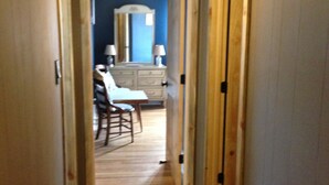 A hallway with wooden flooring leading to a room with a dresser, mirror, and chair. - Nita s Place 2 Bedroom Holiday Home By Pinon Vacation Rentals (Salida)