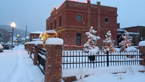 A brick building with a snow-covered fence and Christmas lights.