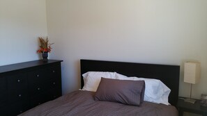 A neatly made bed with a brown quilt, a dark headboard, and a small bedside table with a lamp. - River City Town House 3 Bedroom Holiday Home By Pinon Vacation Rentals (Salida)