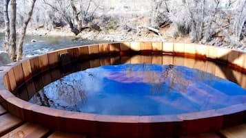 A wooden hot tub with a curved edge, surrounded by a wooden deck.