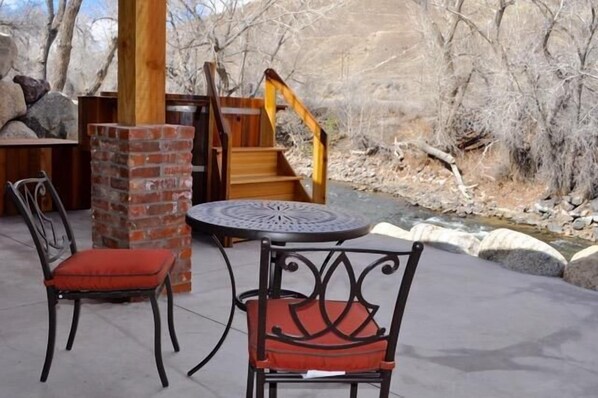 Une terrasse extérieure avec deux chaises, une table et une structure en bois reposant sur une base en briques.