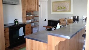 A kitchen with wooden cabinets, a stainless steel countertop, and a microwave. - River House Upstream 2 Bedroom Holiday Home By Pinon Vacation Rentals (Salida)