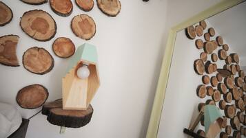 Una habitación con una instalación artística de madera, un comedero para pájaros de madera y un espejo que refleja la obra.