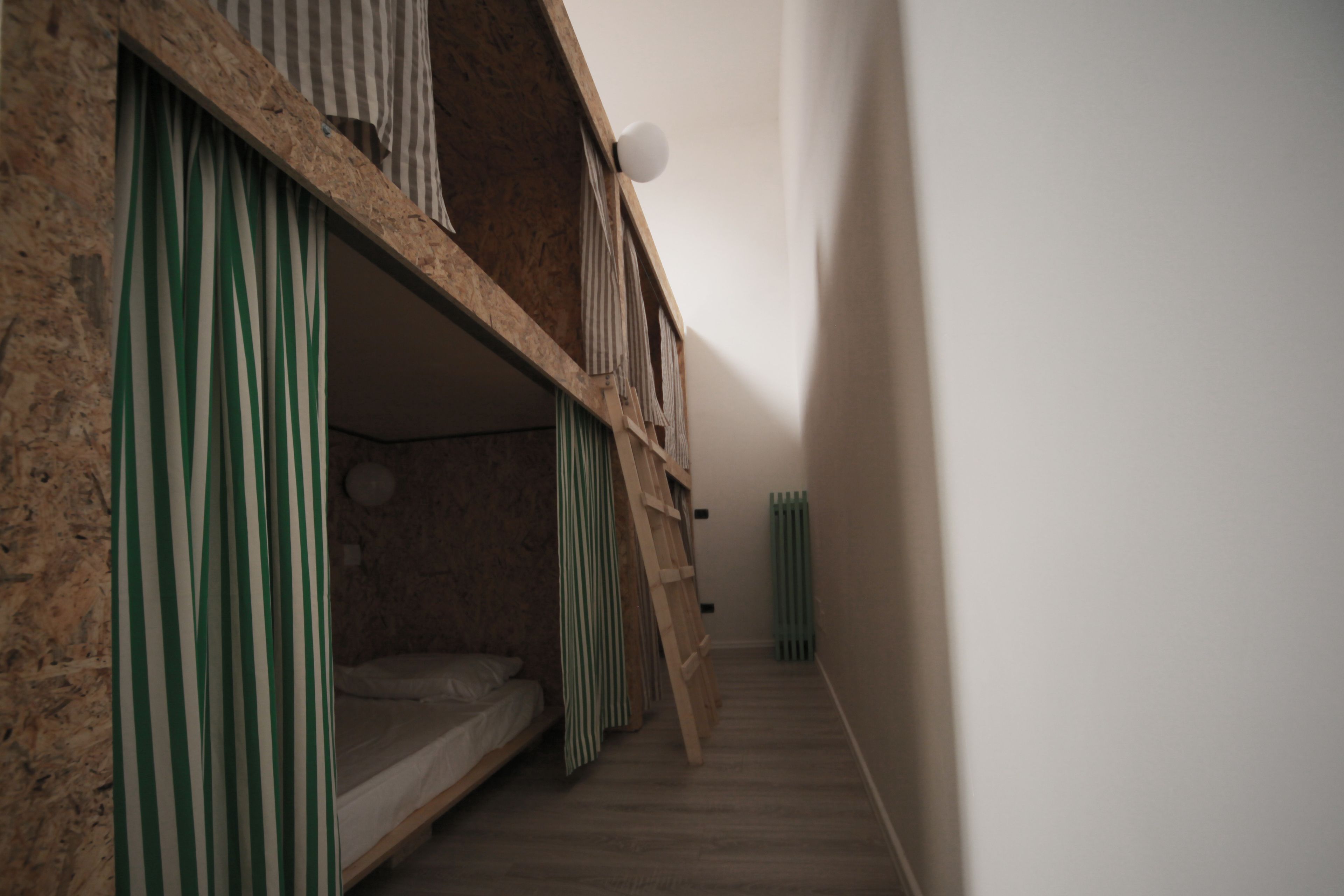 A narrow hallway with a bunk bed on the left, wooden walls, and a radiator on the right.