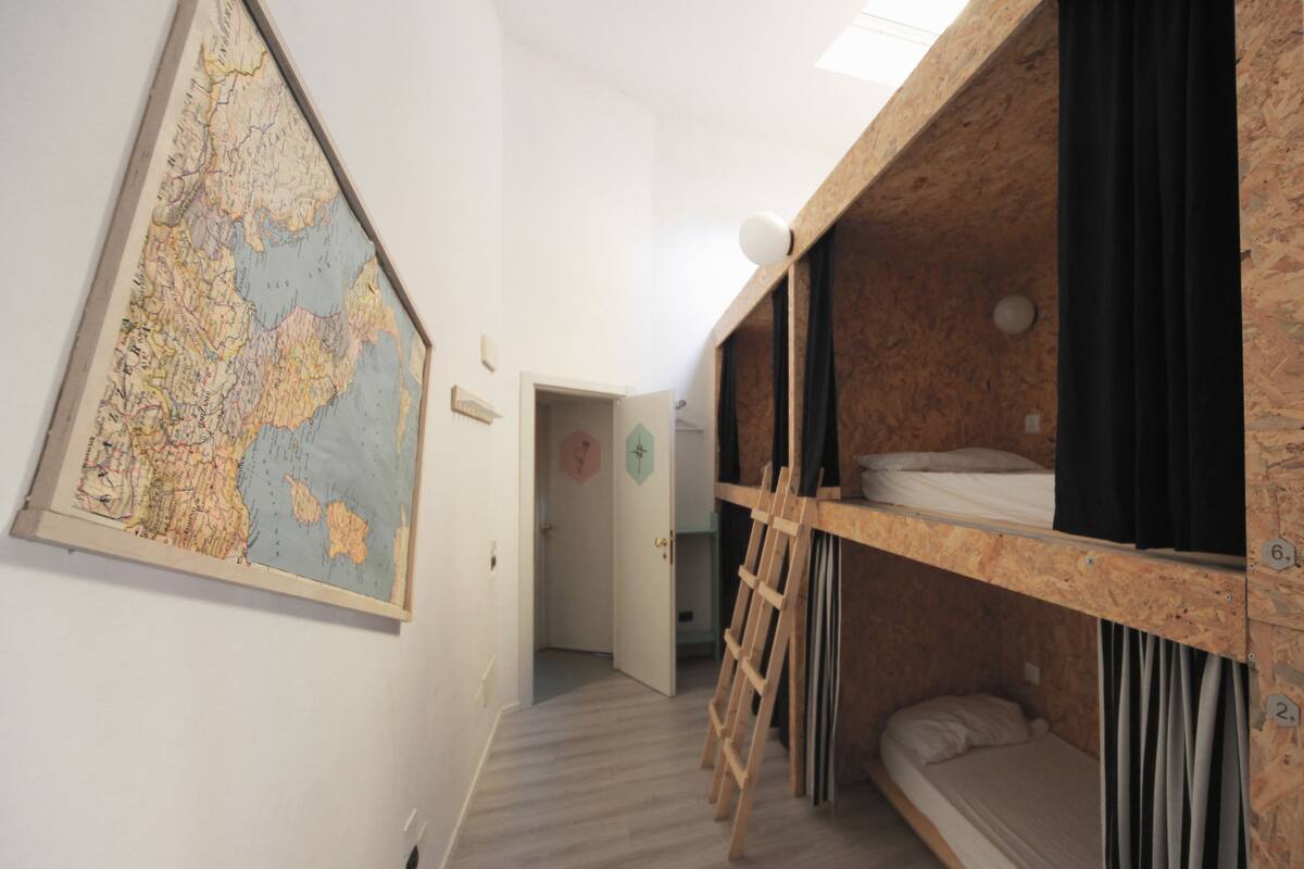 A room with bunk beds, a wooden ladder, a map on the wall, and a door leading to another room.
