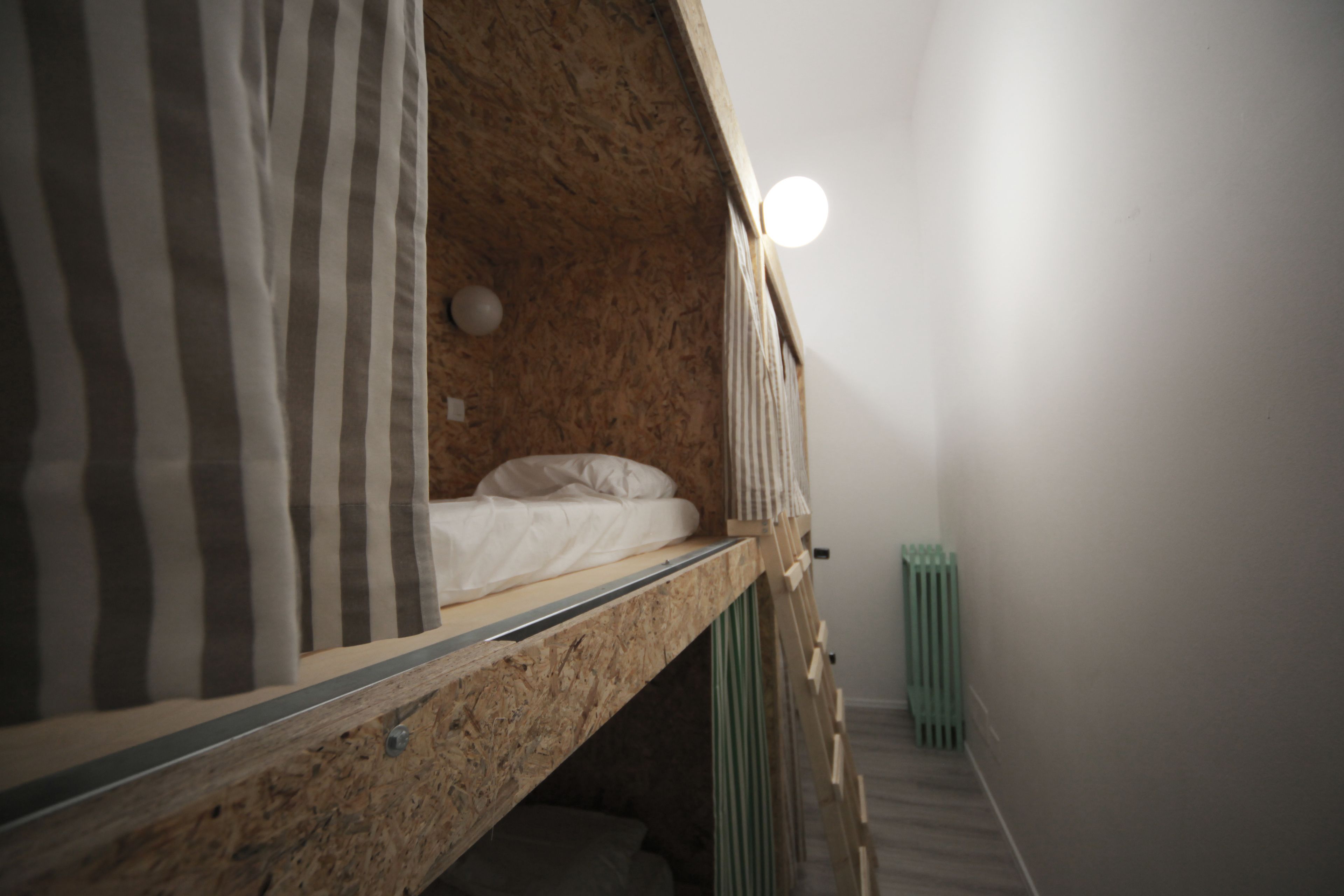 Ein Etagenbett mit Holz Kopfteil, einer weißen Matratze und Streifen Vorhängen.