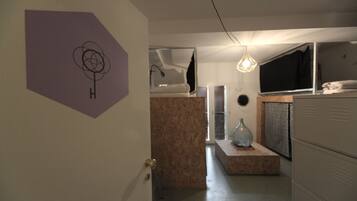 Ein Zimmer mit Etagenbett, Schreibtisch, Stuhl, Lampe und einem Wandregal.