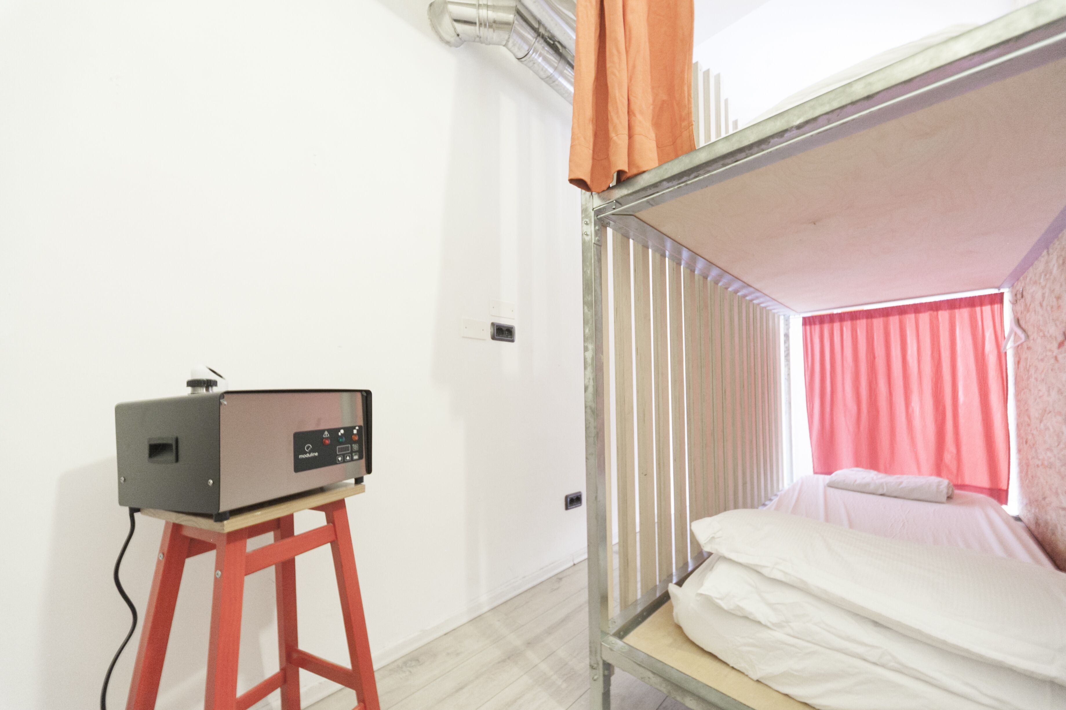 Una habitación con literas, una mesita y un ventanal con cortinas.