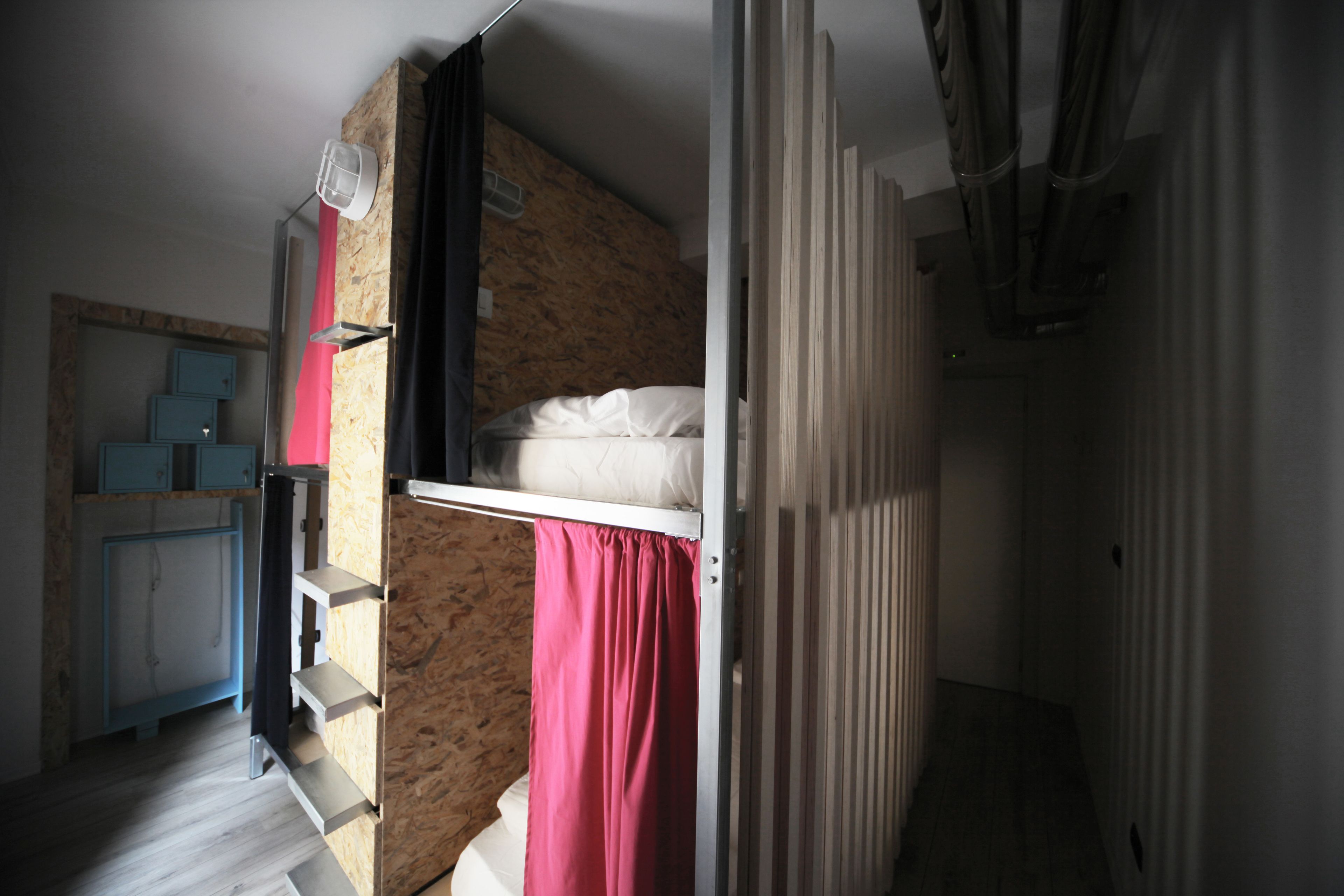 Habitació senzilla amb un llit superposat, una cuineta petita i una paret de ressalt decorada amb fusta.