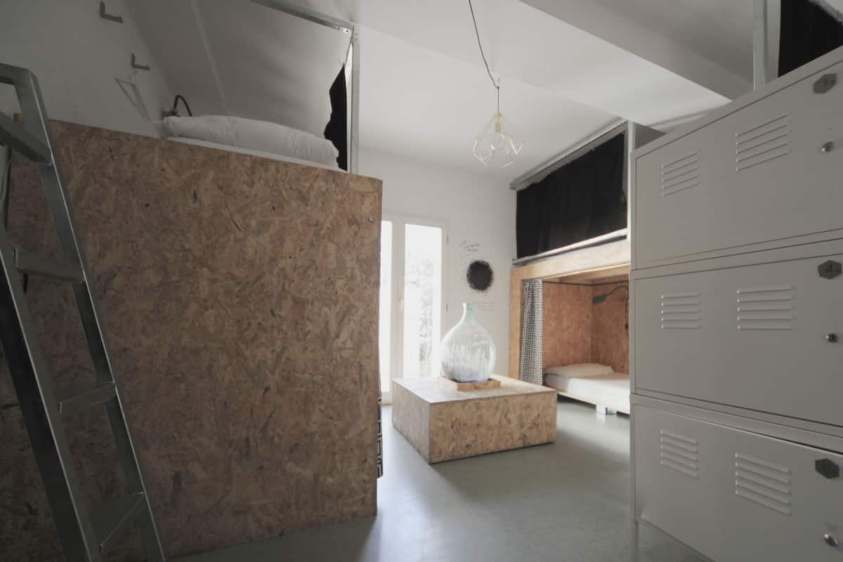 A modern, compact room with a bunk bed, a ladder, a desk, and storage lockers.