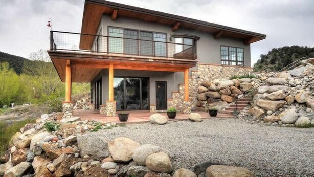 A modern two-story house with a stone facade, large windows, and a covered porch. - River Time 1 Bedroom Holiday Home By Pinon Vacation Rentals (Salida)