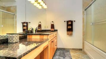 A bathroom with a granite countertop, wooden cabinets, a large mirror, and a towel rack.