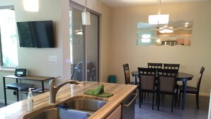A modern kitchen with a double sink, stainless steel appliances, and a dining area with a round table and chairs.