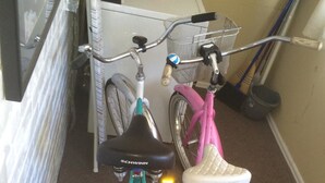 Two bicycles, one teal and one pink, parked indoors.