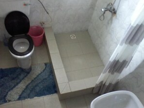A bathroom with a toilet, a shower, and a small sink. - Samartine Hotel (Kwabenya)