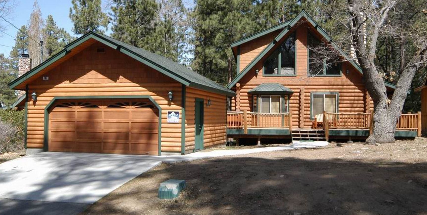 A log cabin with a garage, a covered porch, and a large window.