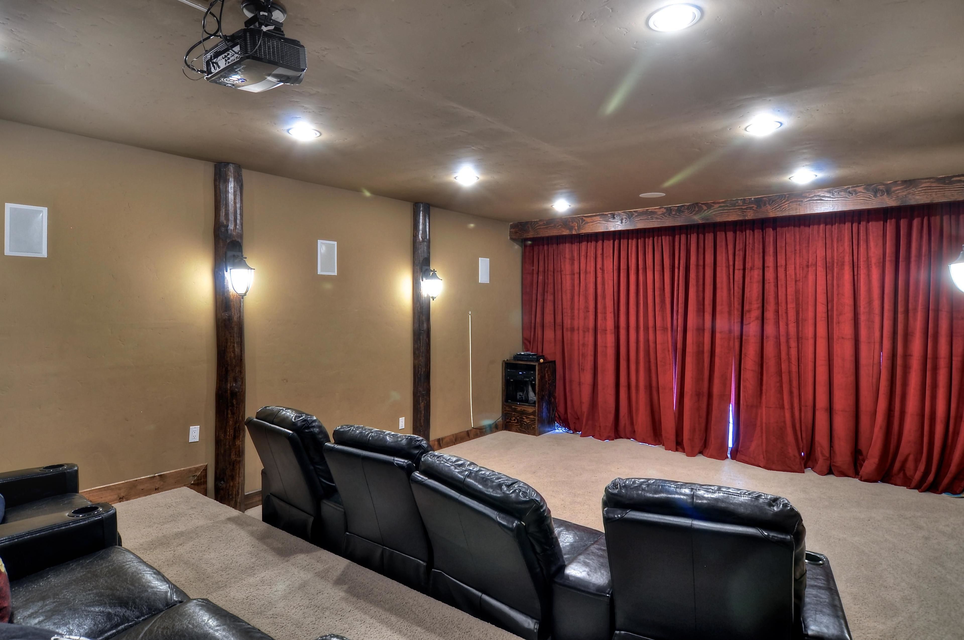 A conference room with a stage, red curtains, and leather chairs.