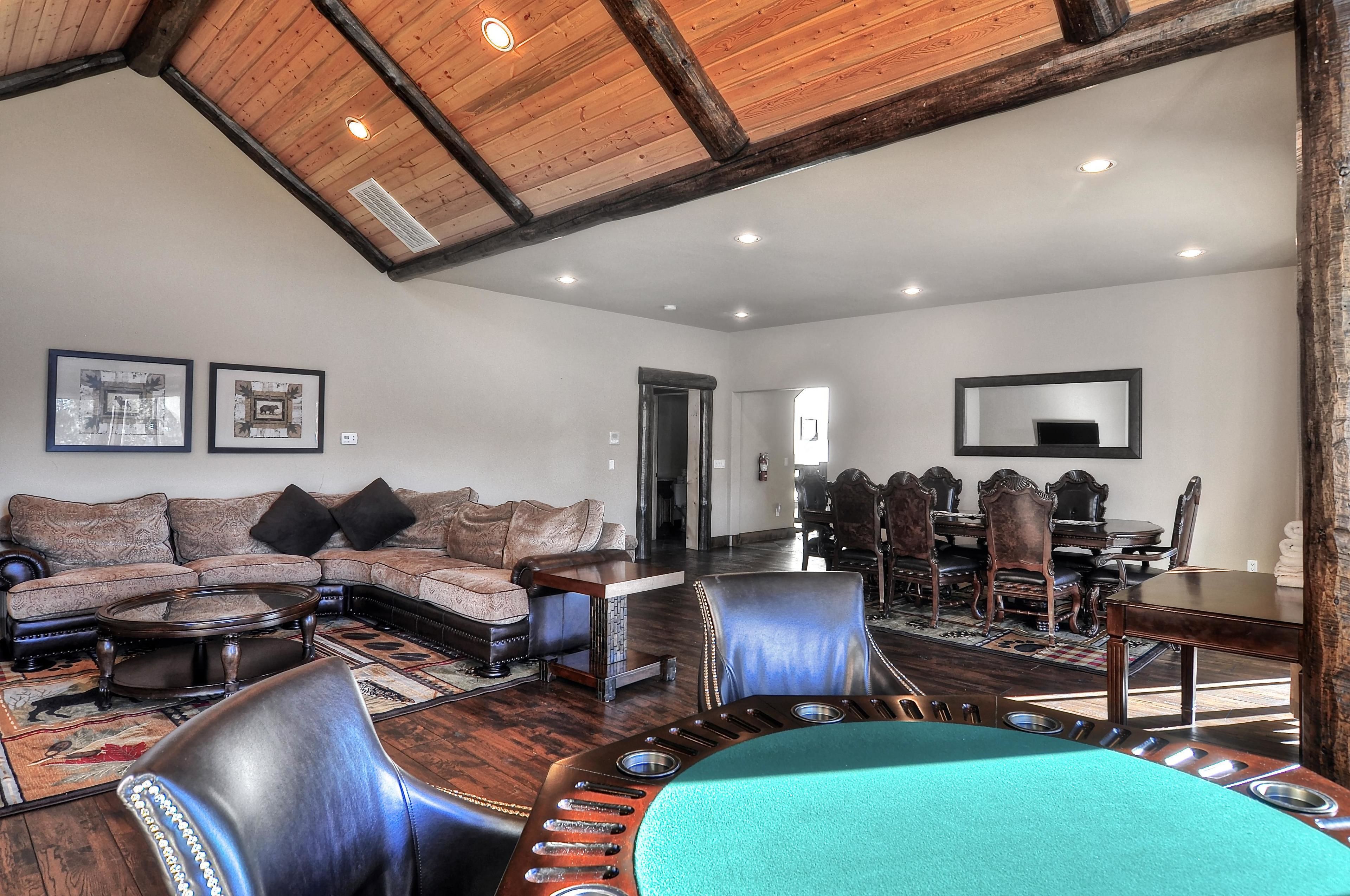 A spacious living room with a large sectional sofa, leather chairs, a coffee table, and a dining area with a wooden table and chairs.