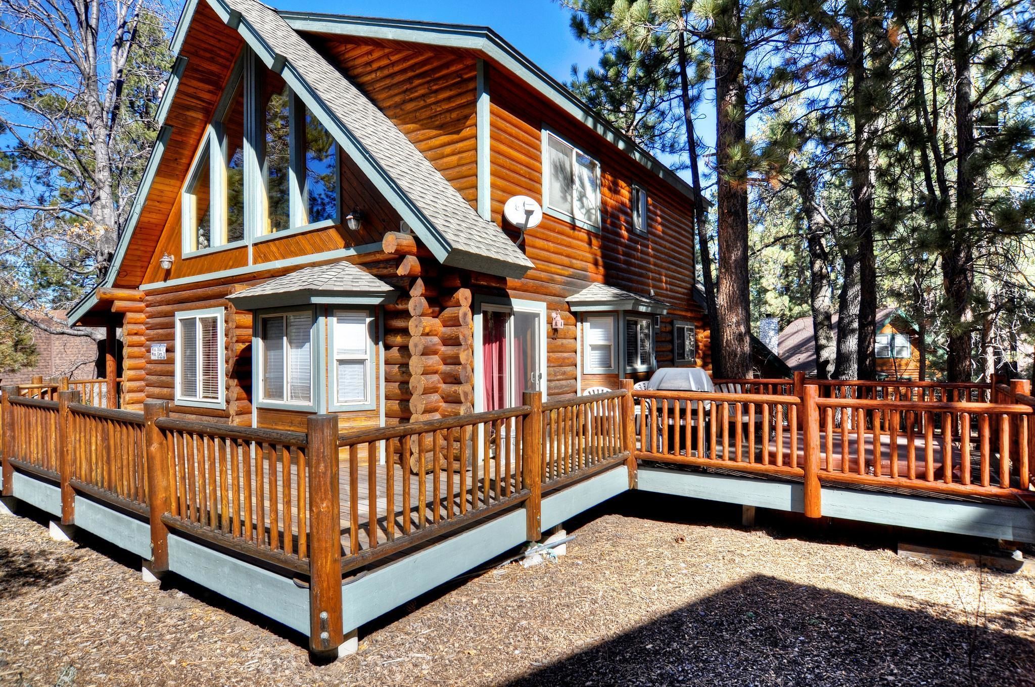 A log cabin with a wooden deck and a fenced porch.