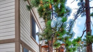 A two-story house with a stone foundation, a wooden deck, and a staircase leading to a balcony.