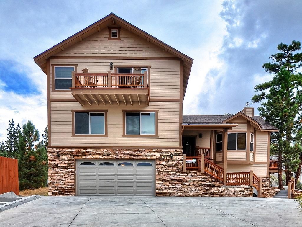 A two-story house with a stone foundation, a balcony on the upper floor, and a garage.