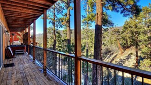 A wooden deck with a railing overlooking a forested area.