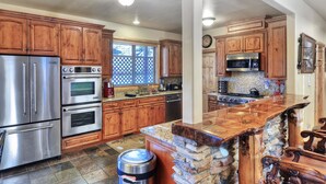A kitchen with wooden cabinets, stainless steel appliances, a granite countertop, and a stone island.