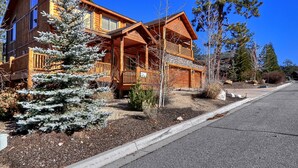A wooden cabin with a balcony, surrounded by trees and a clear sky.