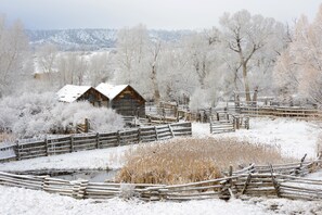 A rustic wooden cabin surrounded by a snow-covered landscape with a wooden fence and a small pond. - Dunwell Cottage 2 Bedroom Holiday Home By Pinon Vacation Rentals Cottage (Salida)