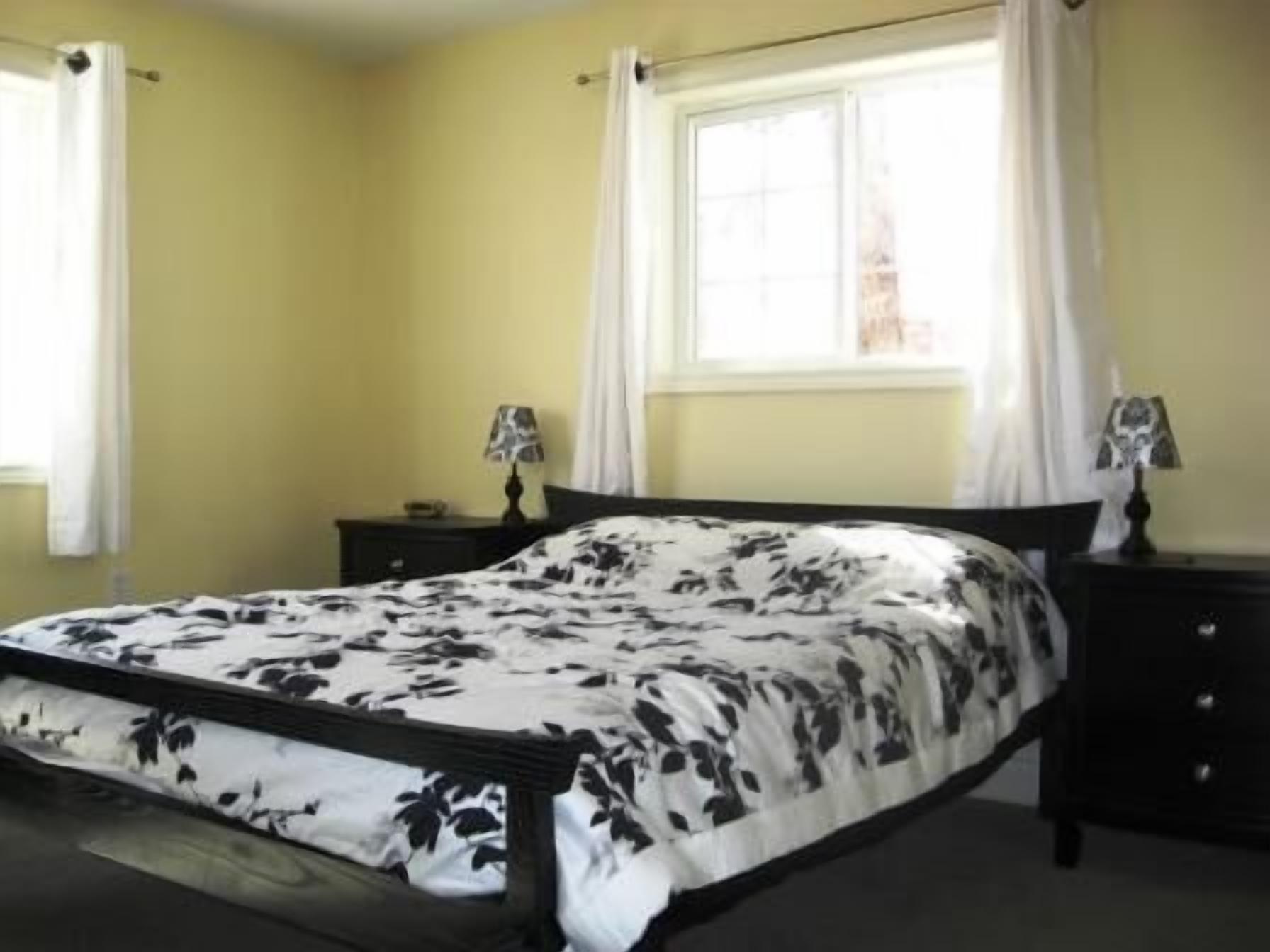 A bedroom with a bed, two bedside tables, and a window with curtains.