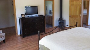 A bedroom with a bed, dresser, television, and a wood-burning stove. - River Lover's 3 Bedroom Holiday Home By Pinon Vacation Rent. (Howard)