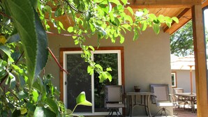 A covered patio with outdoor furniture, a sliding glass door, and a view of the surrounding greenery. - River Lover's 3 Bedroom Holiday Home By Pinon Vacation Rent. (Howard)