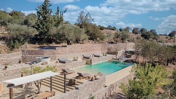 Relax by the serene pool surrounded by lush greenery and stone walls.