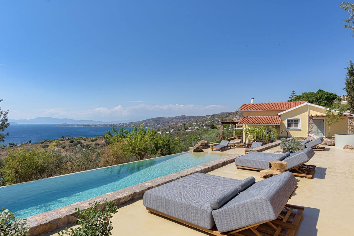 Un espace aménagé au bord de la piscine, avec des chaises longues et une vue sur la mer.