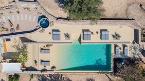 Luchtbeeld van een resort met een zwembad, ligbedden en een klein tuintje.