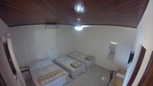 Una habitación con dos camas, un ventilador de techo, un espejo y piso de baldosas.