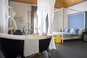 A modern bedroom with a black bathtub, a canopy bed, and a bedside table with a mirror and candles. - Curù (Castellammare del Golfo)