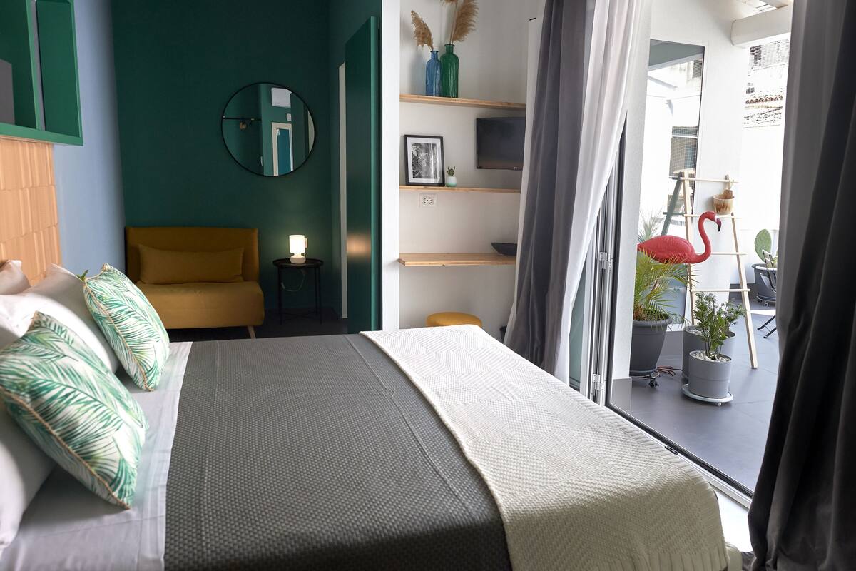 Ein modernes Schlafzimmer mit Bett, Nachttisch und Blick auf den Balkon.