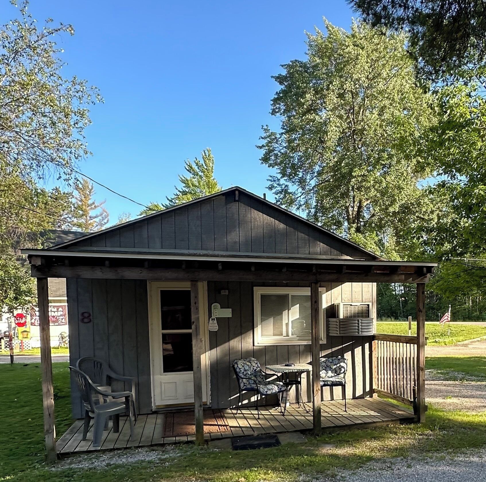 Une petite cabane en bois avec une véranda, une porte et une fenêtre.