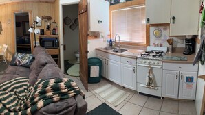 A compact living space with a kitchenette, a dining area, and a sofa with a blanket.