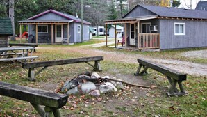 A campground with two cabins, picnic tables, and a fire pit.