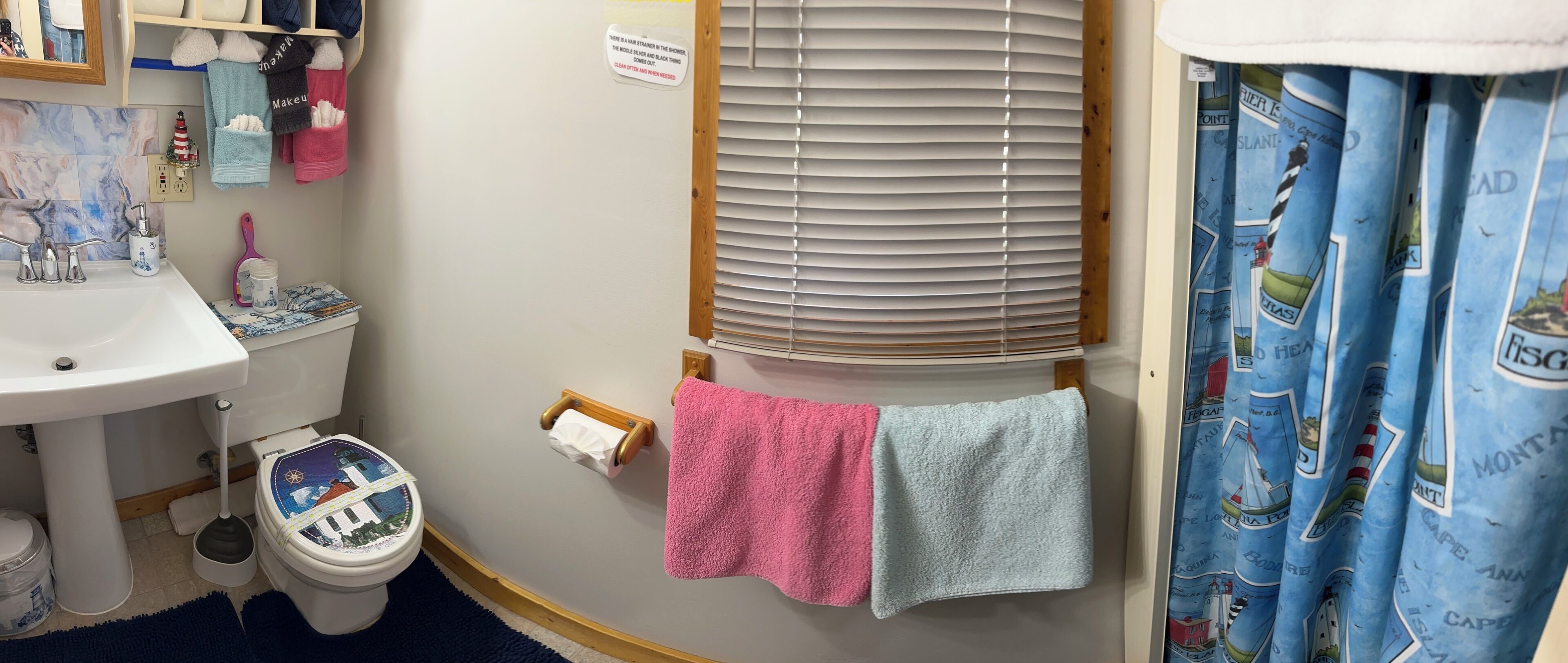 Et badeværelse med toilet, vask, skodder og bruseforhæng.